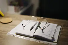 Отворен бележник и химикалки на бюро