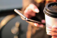 Смартфон и чаша кафе в ръце